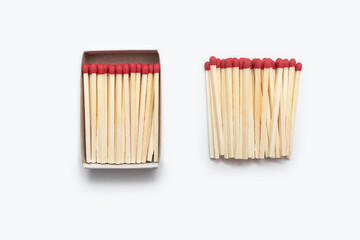 Matches in an open matchbox and many matches near the matchbox isolated on white background. Red matches on a white background are vertically arranged. Top view of matches close-up with space for text