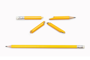 Broken and whole pencil on a white horizontal background. Two yellow graphite pencils broken into many parts and whole close-up. Emotions, stress, anger, aggression, problems in studies, at work