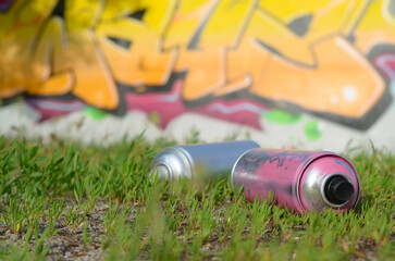 Several used spray cans with paint and caps for spraying paint under pressure on grass near the...