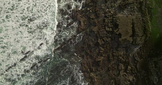 Plano cenital de las olas golpeando las rocas