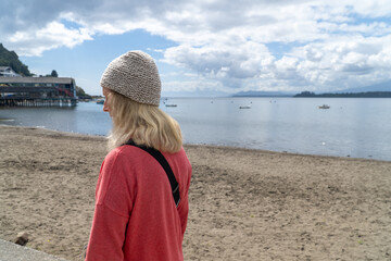 Blonde woman in her 50s strolling through a village with a beautiful lake in winter, sightseeing in Chile.