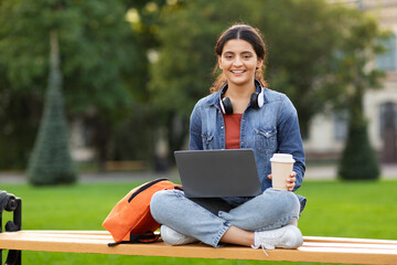 Positive young indian woman student doing homework outdoors