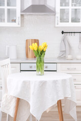 Home kitchen interior.Vase with bouquet of yellow tulips on table. Spring consept.
