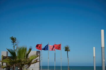Fototapeta premium Moroccan, Spanish, European Union, USA and Great Britain flags over blue sky background