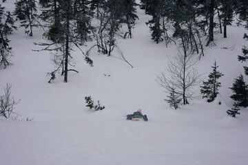 a kid sliding down a slope on the stomack in the snow