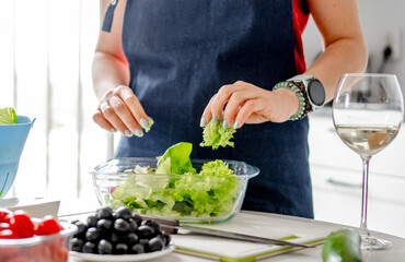 Woman Tears Lettuce Leaves Into Bowl For Making Greek Salad - 755127121