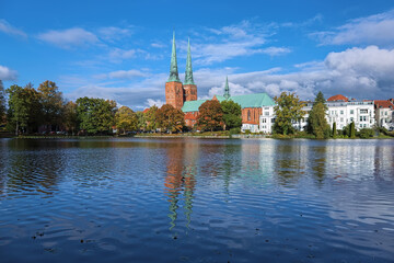 Lubeck, Germany. View of Lubeck Cathedral from the opposite shore of Muhlenteich (Mill pond) in autumn day. The cathedral was started in 1173 and consecrated in 1247. - 755128935