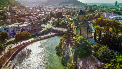 Drone point of view Downtown of TbilisiL landmark - Metekhi church, old town on another side of river Kura  in sunny lights of   Georgian summer © Marat Lala
