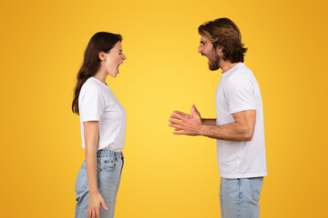 Obraz premium Intense young couple in white t-shirts engaging in a verbal disagreement or animated conversation