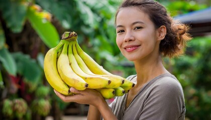 A young woman holding a bunch of bananas, smiling 