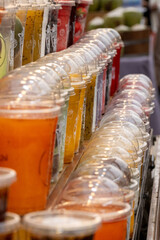 Several fresh fruit juices on display at a food stall at a street food market in Pattaya, Thailand.