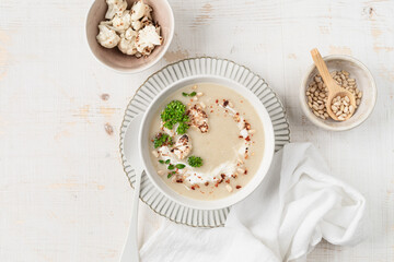 Cauliflower cream soup with pine nuts in a bowl on a white background