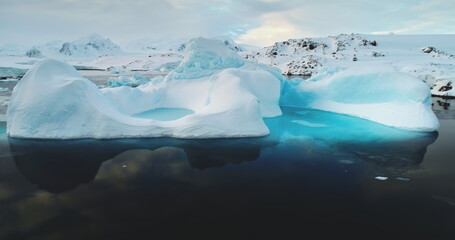 Global warming, melting icebergs in Antarctica. Glacier with melted cavity floating in blue ocean water. Polar climate change at sunny winter day. Cinematic ecology scene. Close up shot © mozgova