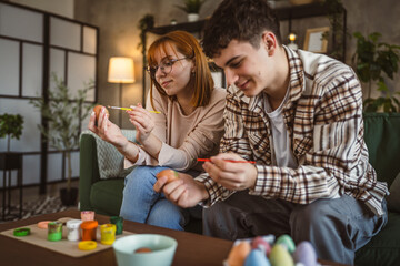 young man and woman couple or brother and sister paint easter eggs