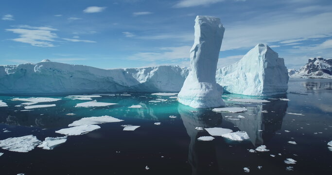 Towering melting iceberg global warming concept. Snow covered glacier float turquoise ocean water in sunny summer day. Polar climate change issue. Wild Antarctica nature environment. Close up panorama