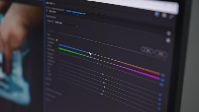 Close-up of video maker editing movie, making color correction using modern software app. Program interface with color tools, RGB wheels and levels on PC screen. Film post production concept.