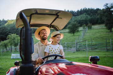 Farmer father riding tractor with his daughter. Girl growing up on family farm. Concept of...