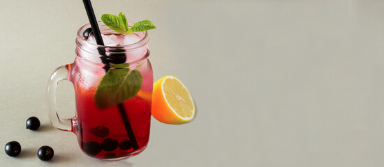 Cold lemonade or infused water with black currant, lemon and mint on the gray background. Copy space. Close-up.