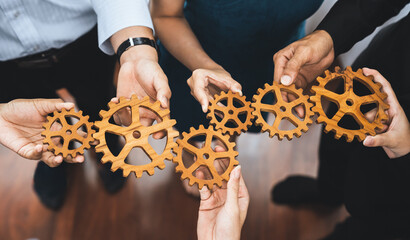 Office worker holding cog wheel as unity and teamwork in corporate workplace concept. Diverse...