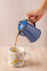 mano de mujer sirviendo cafe caliente en una taza con dibujos de pajaros