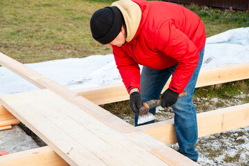 A man in a red jacket is engaged in construction using wooden planks - 755148748