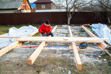 A man in a red jacket is engaged in construction using wooden planks - 755149144