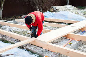 A man in a red jacket is engaged in construction using wooden planks - 755149529