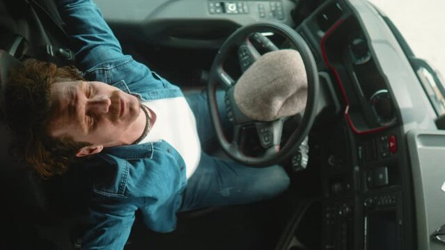 The truck driver sits in the cab and stretches, feeling discomfort in his spine and neck