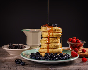 high stack of pancakes with berries on black background