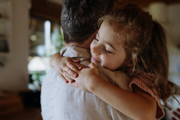 Daughter hugging father lovingly, closed eyes. Unconditional paternal love, Father's Day concept.