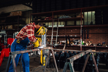 Worker in a dangerous work environment welding metal with the machine.