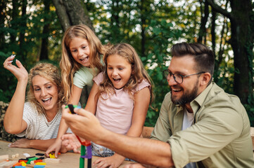 A fun family playing with wood tiles toy in nature.