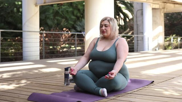 curvy woman doing yoga outdoors