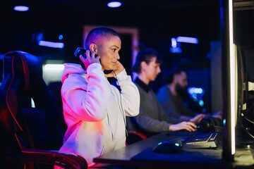 Bald female gamer putting headphones on in cyber club and playing video games © Zamrznuti tonovi