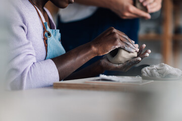 Obraz premium Close up of interracial pottery class student's hands making earthenware