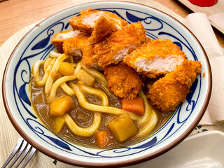 A bowl of chicken katsu curry with udon noodles at a Japanese restaurant