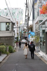 A Japanese couple of young men and women in their 20s walking down a street. High quality photo