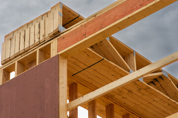 Floor joists stacked on top  of first floor of  multi story wood frame apartment building under construction.