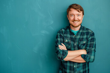 Friendly Smiling Man with Crossed Arms in Plaid Shirt Against Teal Background: Casual Confidence Personified