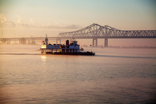Morning Boat Ride on the Mississippi. A ferry boat is seen traversing calm waters, with the early morning light casting a warm glow over the scene. 