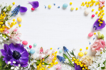 White wooden background with colorful bright flowers, candy eggs and copy space. Decorative floral card for Easter holiday. - 755170396