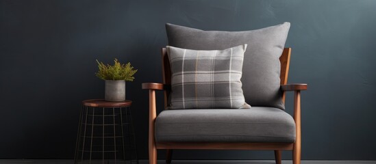 A stylish armchair with a pillow and plaid sits near a dark wall, next to a small wooden table. On the table is a small plant in a pot, creating a cozy and inviting corner in a room.