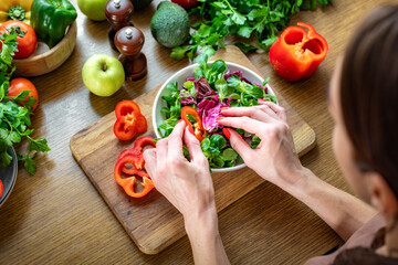 Healthy lifestyle concept. Female hands cooking a dietary summer salad at home in the kitchen, top...