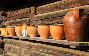 Many old clay pots on a wooden shelf