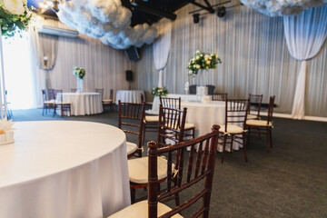 Decorated interior for festive event. Fancy table set for dinner with flower composition in restaurant, luxury interior background. Wedding elegant banquet decoration arranged by catering service