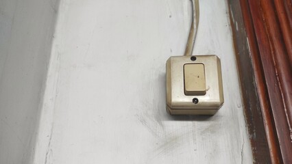 A white switch on the wall to turn on and turn off the lamp in the room