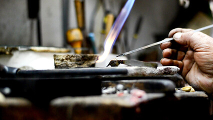 Fototapeta na wymiar Master jeweler welding an ornament in a jewelry workshop. Image of hands and product close up.