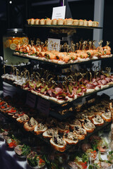 Beautifully decorated catering banquet table with different food snacks and appetizers with sandwich, caviar, fresh fruits on corporate christmas birthday party event or wedding celebration.