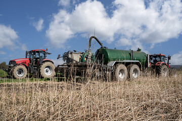 Umpumpen von Gülle aus einem Transportfahrzeug in das Güllefass auf einem Feld im Frühjahr.