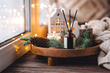 Creating cozy holiday Christmas home atmosphere. Liquid reed diffuser with sticks with xmas scent: vanilla, gingerbread cookies, pine, sweet pie, cinnamon, anise. Aromatherapy, wellness, relaxation